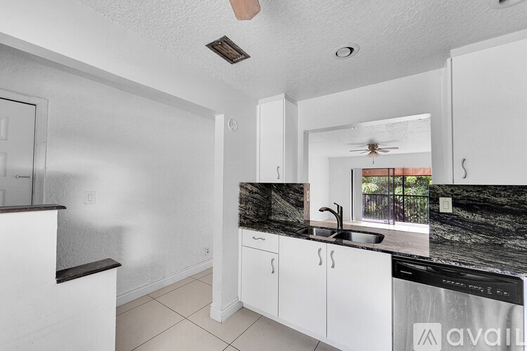 A kitchen with white cabinets and a black countertop.