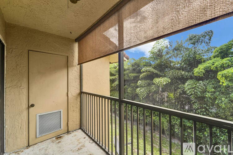 A balcony with a door and a window overlooking a lush green landscape.
