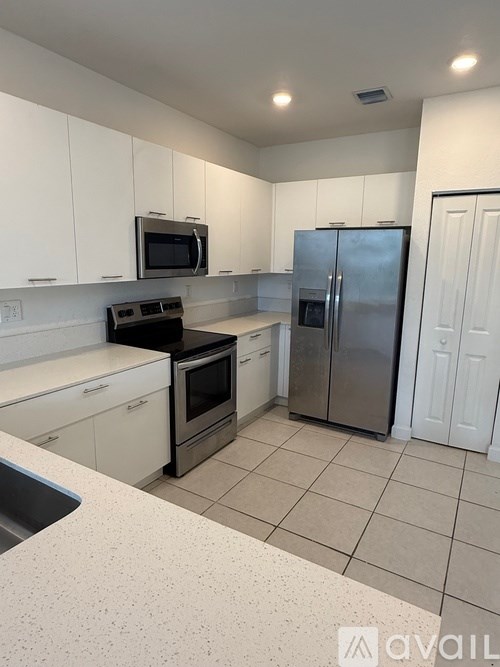 A kitchen with white cabinets and a stainless steel refrigerator.