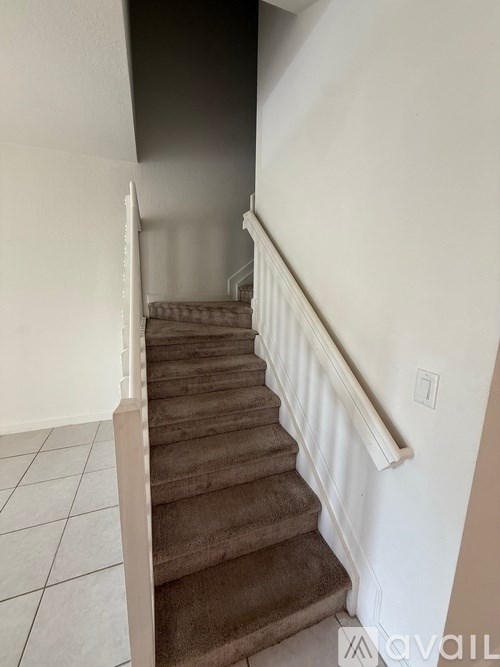 A staircase with a white railing and brown carpeted steps.