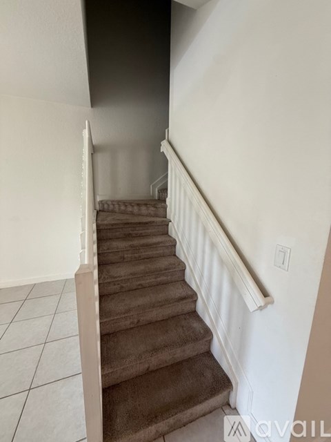 A staircase with a white railing and brown carpeted steps.