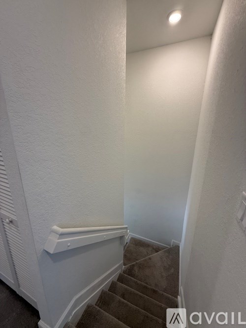 A stairway with a carpeted runner and white walls.