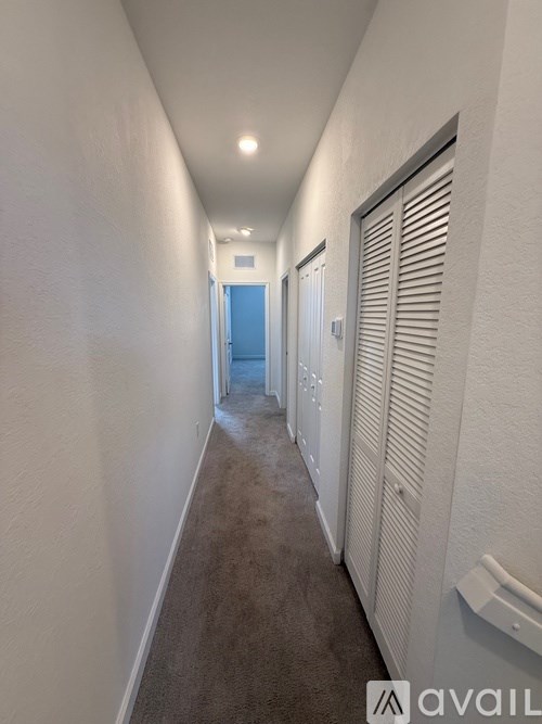 A long hallway with a carpeted floor and white walls.