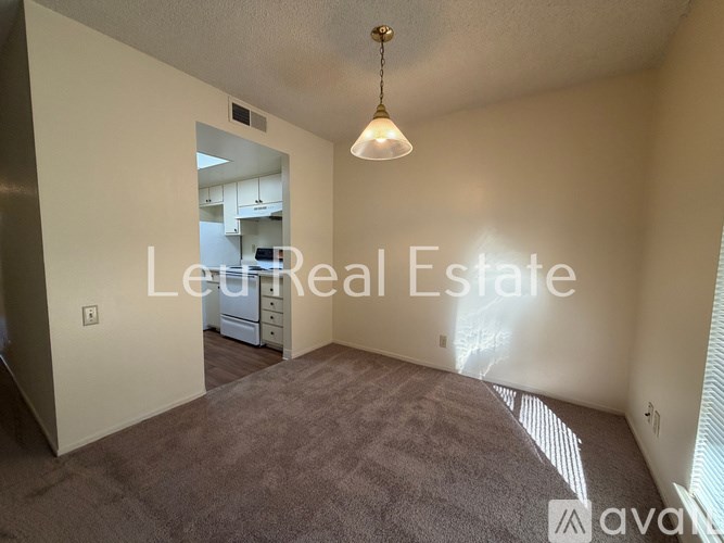 A room with a carpeted floor and a hanging light fixture.