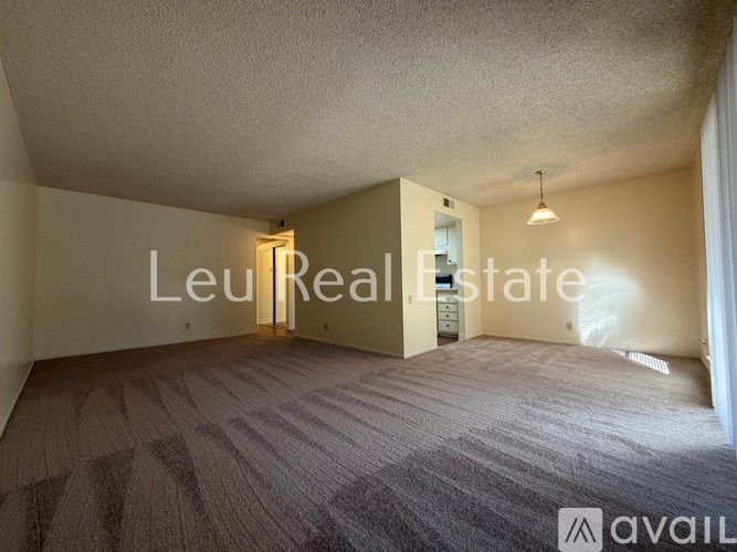 A room with carpeted floor and a text that reads "Leu Real Estate".