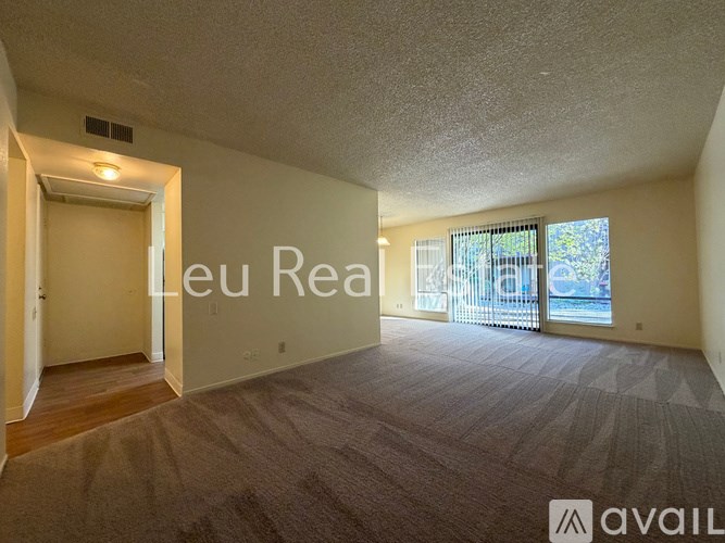 A room with a carpeted floor and a door leading to a balcony.