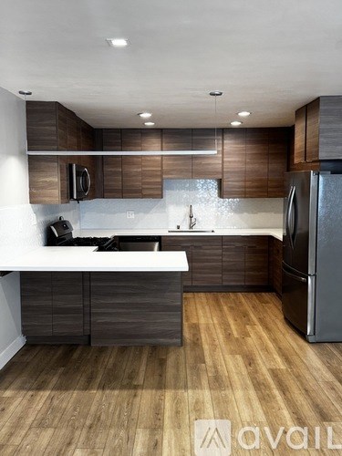 A modern kitchen with wooden cabinets and a stainless steel refrigerator.