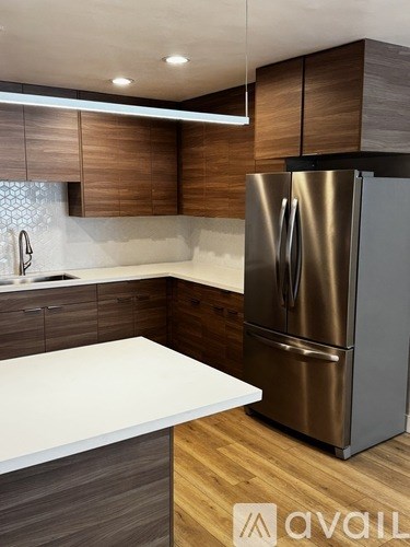 A modern kitchen with a stainless steel refrigerator and wooden cabinets.