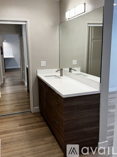 A bathroom with a white sink and brown wood cabinets.