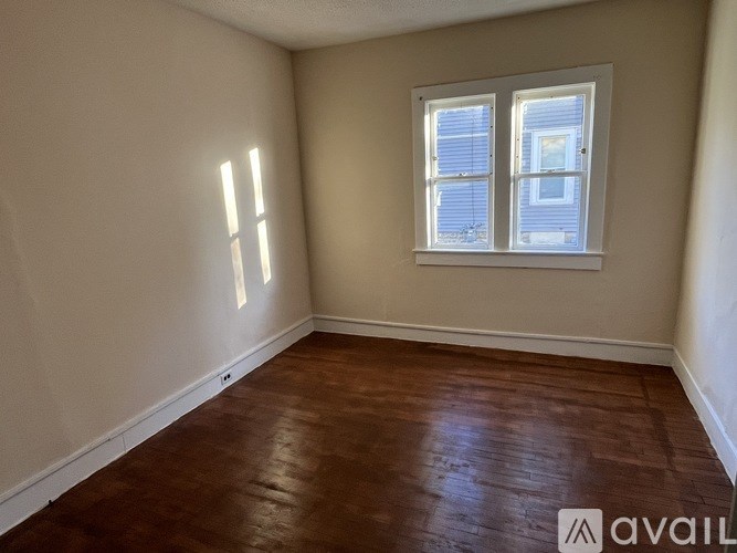 A room with a wooden floor and a window with blinds.