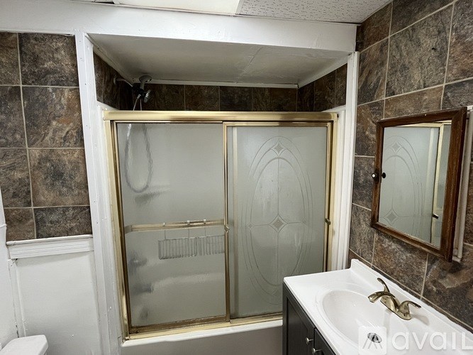 A bathroom with a glass shower door and a white sink.