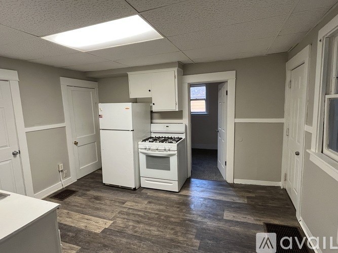 A kitchen with white appliances and wooden floors.