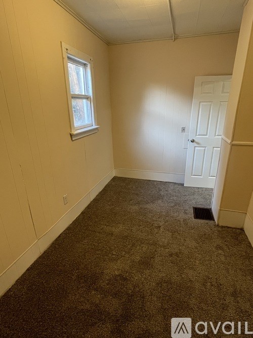 A room with a carpeted floor, a door, and a window.
