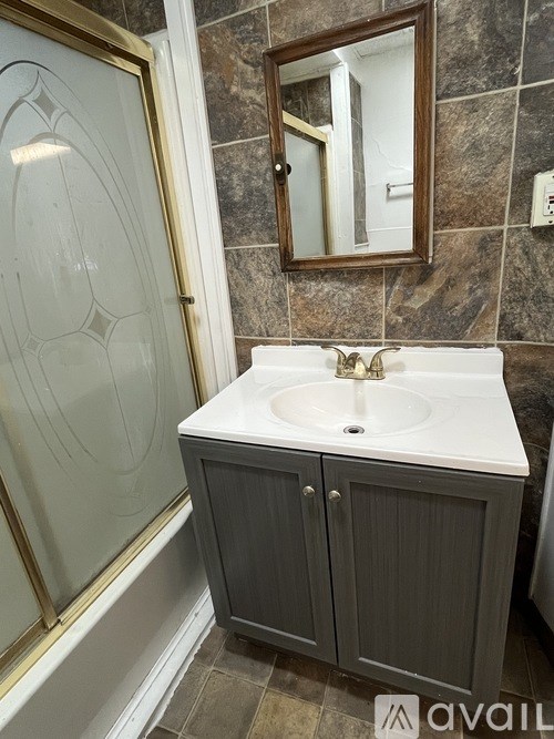 A bathroom with a sink, mirror and cabinet.