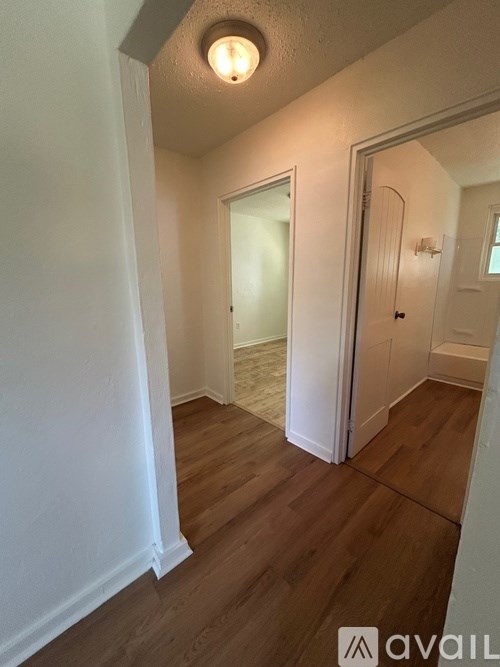 A hallway with wood flooring and white walls.