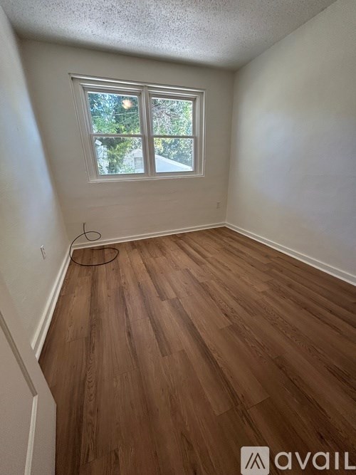 A room with a window and wooden flooring.