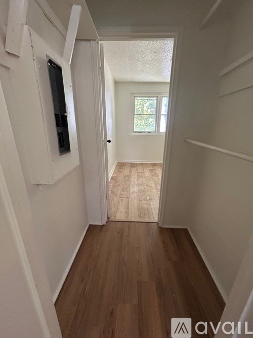 A hallway with a doorway leading to a room with a window.