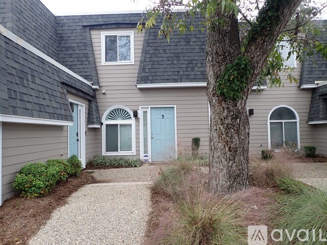 A house with a blue door and a tree in front.