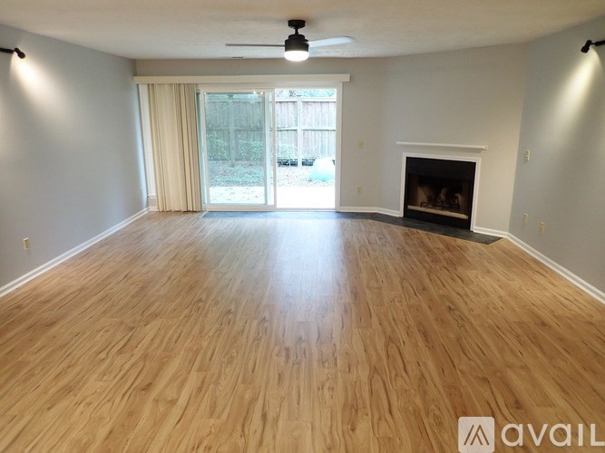 A spacious room with wooden flooring and a fireplace.