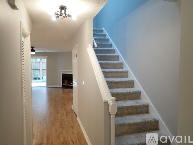 A staircase with a carpeted runner and white balusters leads up to a second floor.