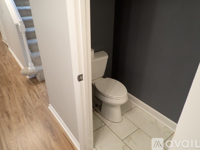 A white toilet in a bathroom with a wooden floor and a staircase.