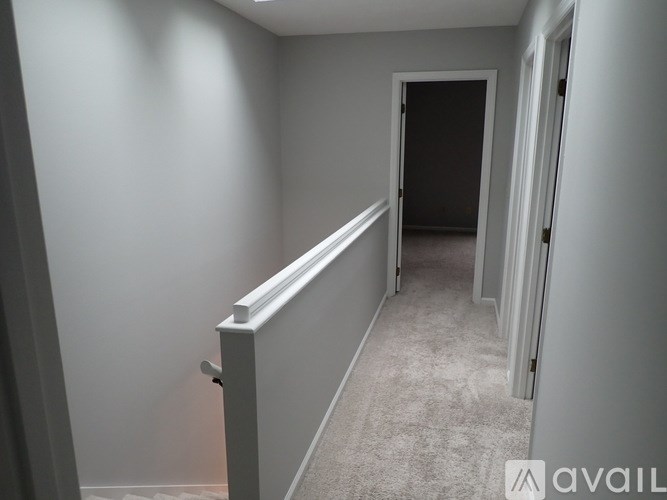 A hallway with a carpeted floor and white walls.