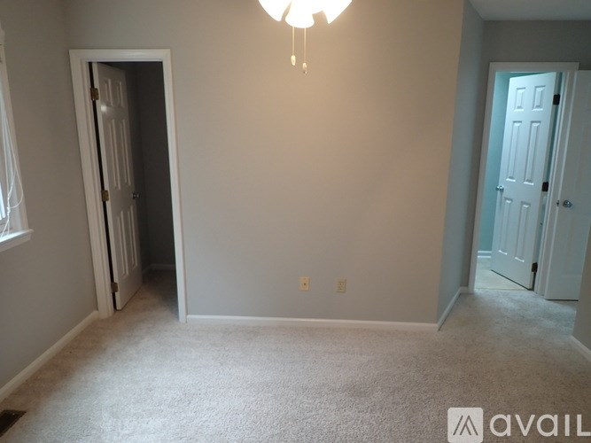 A room with a carpeted floor and a chandelier hanging from the ceiling.