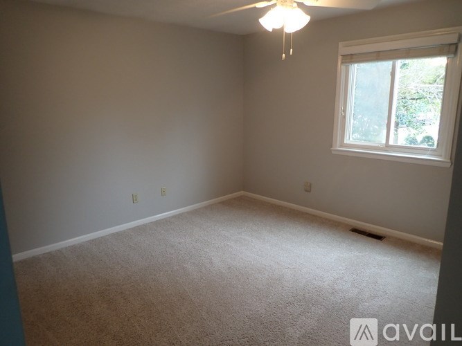 A room with a carpeted floor and a ceiling fan.