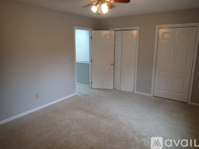 A room with a carpeted floor and a ceiling fan.
