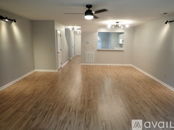 A spacious room with wooden flooring and a ceiling fan.