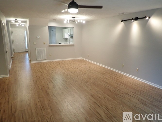 A spacious room with wooden flooring and a ceiling fan.