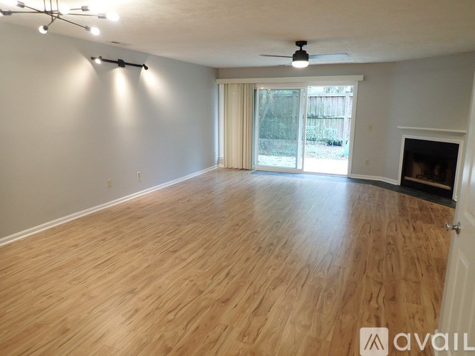 A spacious room with wooden flooring and a fireplace.
