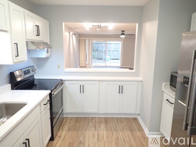 A kitchen with white cabinets and a window.