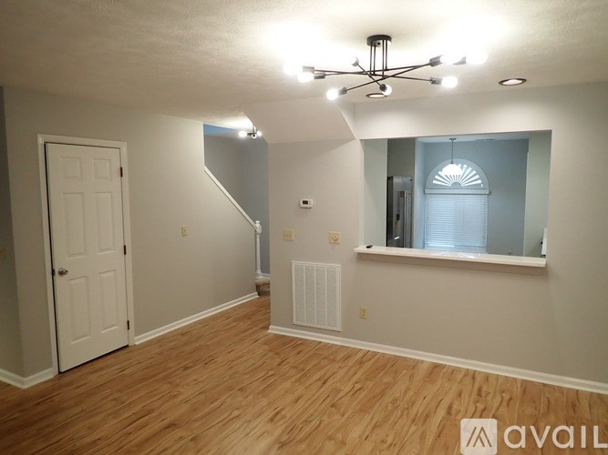 A room with a white door, a window with blinds, and a light fixture on the ceiling.
