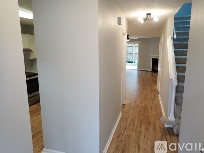 A long hallway with a staircase on the right and a kitchen area on the left.