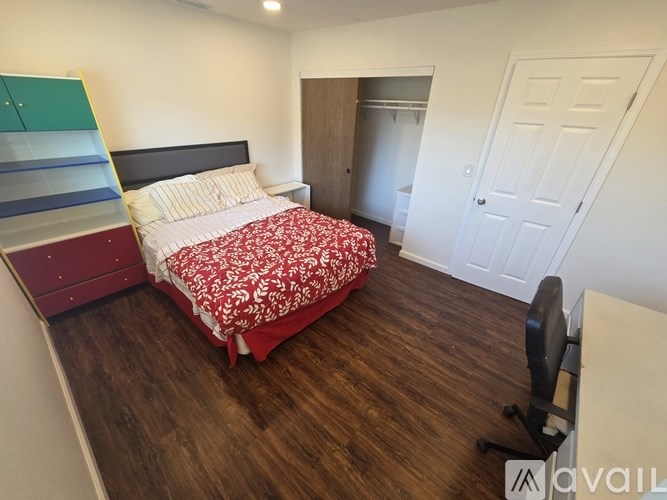 A bedroom with a bed, a chair, and a desk.