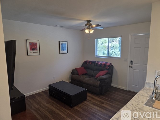A living room with a couch, a coffee table, and a ceiling fan.