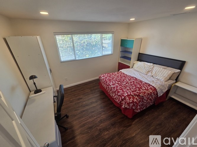 A bedroom with a red bedspread and a white bed.