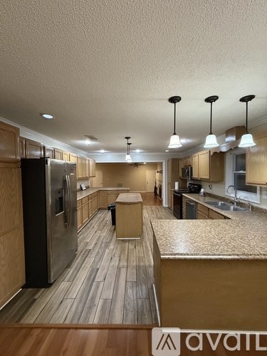 A kitchen with wooden floors and a refrigerator on the left.