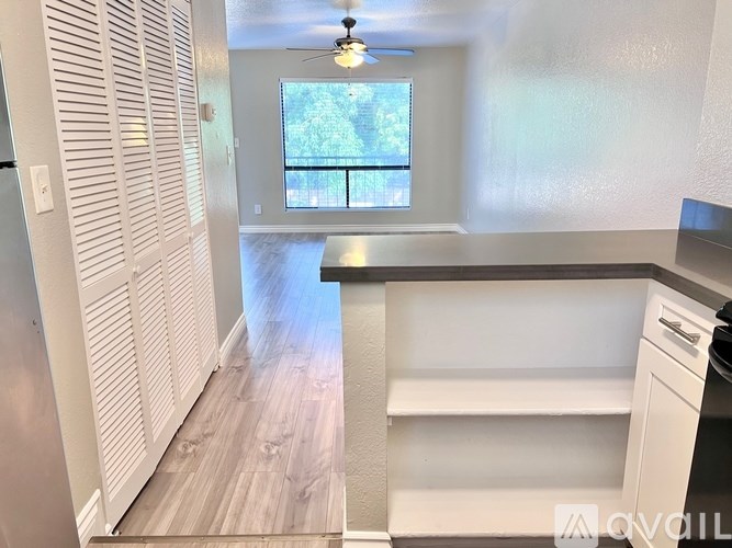 A kitchen with white cabinets and a window with a view of trees.