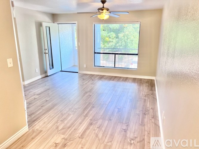 A room with a ceiling fan and sliding glass doors leading to a balcony.
