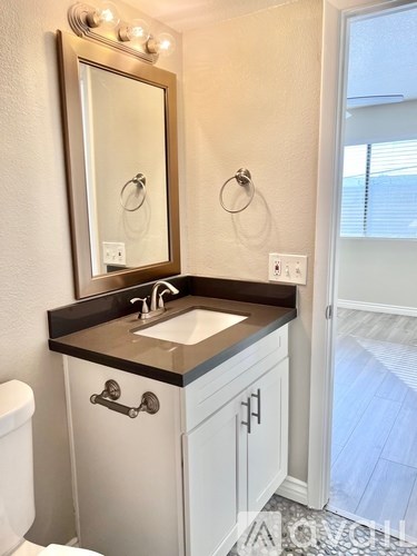A bathroom with a sink, mirror, and toilet.