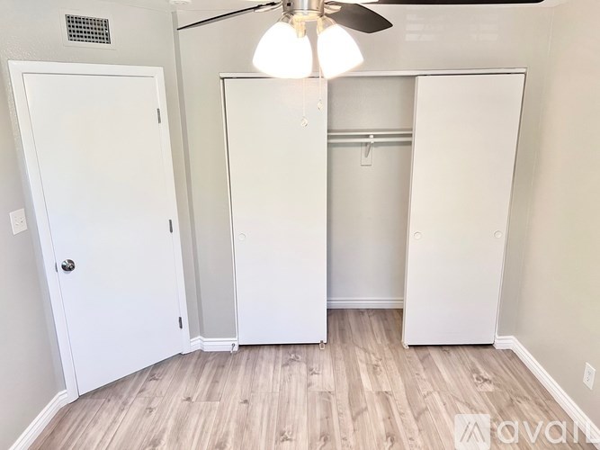 A room with a ceiling fan and three white closets.