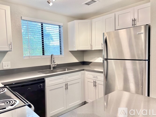 A kitchen with white cabinets and a stainless steel refrigerator.