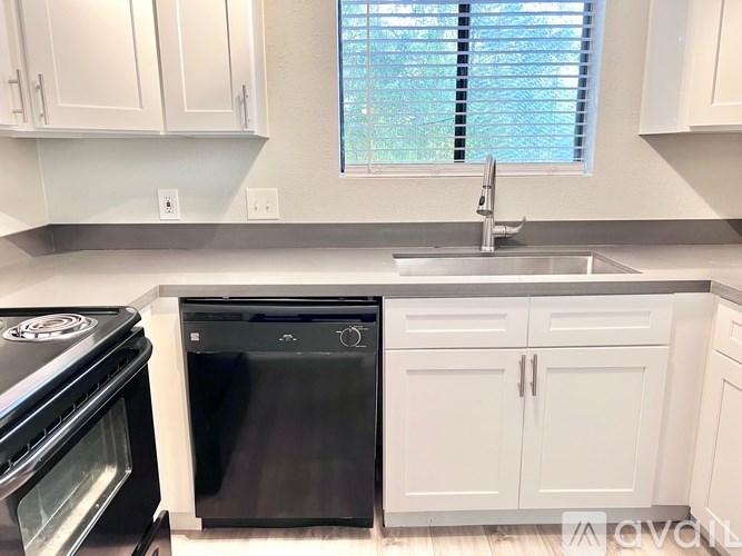 A kitchen with white cabinets and a black dishwasher.