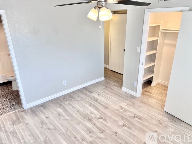 A room with a ceiling fan and a white wall.
