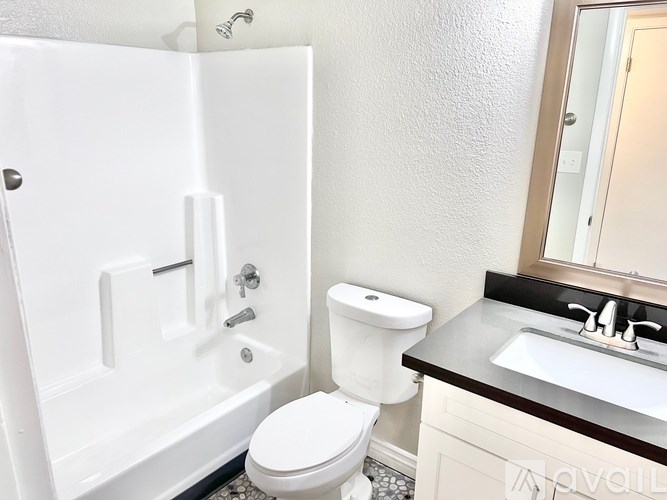 A white toilet sits next to a white bathtub in a bathroom.