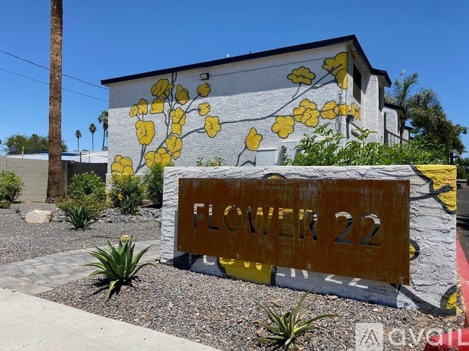 A sign that says Flower 22 in front of a building with yellow flowers painted on it.