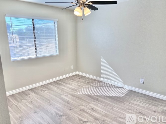 A room with a ceiling fan and a window with blinds.
