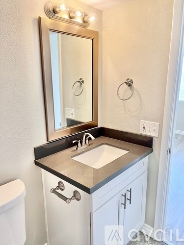 A bathroom with a sink, toilet and mirror.